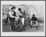 James Baldwin sitting on curb behind street vendor