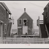 One of the few repair sheds for nets and gear still in operation. Note peaked cap of man seen through open loft door. Provincetown, Massachusetts.