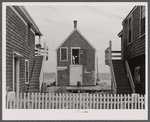 One of the few repair sheds for nets and gear still in operation. Note peaked cap of man seen through open loft door. Provincetown, Massachusetts.