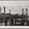 Ruins of former fish pier, Captain Jack's Wharf, a tourist colony which used to be a fish pier and the Pilgrim monument in the background. Provincetown, Massachusetts.