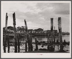 Ruins of former fish pier, Captain Jack's Wharf, a tourist colony which used to be a fish pier and the Pilgrim monument in the background. Provincetown, Massachusetts.