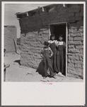 Two sisters and brother before their house. Great Western Sugar Company's beet sugar workers' colony at Hudson, Colorado. The father is dead, and the girls don't attend school because they're "too old," and the boy because he is "sick all the time".