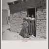 Two sisters and brother before their house. Great Western Sugar Company's beet sugar workers' colony at Hudson, Colorado. The father is dead, and the girls don't attend school because they're "too old," and the boy because he is "sick all the time".