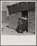 Two sisters and brother before their house. Great Western Sugar Company's beet sugar workers' colony at Hudson, Colorado. The father is dead, and the girls don't attend school because they're "too old," and the boy because he is "sick all the time".
