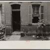 Front of Negro home near Capitol, Washington, D.C. Interiors of these homes vary little. A chair or two and a table, a bed and perhaps an extra mattress on the floor cares for six to ten people.