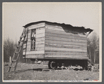This one-room hut built of rough lumber over the chassis of an abandoned Ford truck was the housing provided by a landlord for an illiterate wood-cutter, with a wife and seven children.