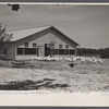 Rehabilitated client, Everett Tune, feeding chickens bought with rehabilitation loan, with laying house in background built by him with rehabilitation loan, Dent County, near Salem, Missouri.