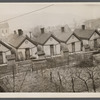 Row of identical houses off Eastern Avenue, in Cincinnati, Ohio, showing backyard outhouses. Ohio River Valley is in the distance.