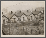 Row of identical houses off Eastern Avenue, in Cincinnati, Ohio, showing backyard outhouses. Ohio River Valley is in the distance.