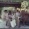 James Baldwin at bamboo-shaded table with guests at his home in France