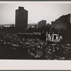 New York Shakespeare Festival Mobile Theater performing Midsummer Night's Dream in New York City playground at night with residential buildings and bridge visible in the background