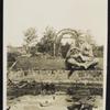 George Arliss with his dog  sitting at the edge of a water feature in a garden