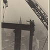 Two construction workers at the corner of two steel beams pointing to the left