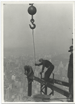 Two workers attaching a beam with a crane