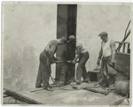 Three workers securing a rivet