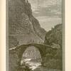 The cliffs of Sûk Wâdy, Barada.  A modern bridge of a single arch spans the river, and the road crosses from the right to the left bank. This is the narrowest part of the gorge, and the cliffs that shut it in are not more than a hundred feet apart.