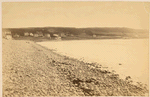 Pebbly beach, hotels and houses in the middle distance