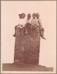 Children sitting on a stone structure, 1902