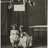 Girls standing beneath tin ware, 1910s