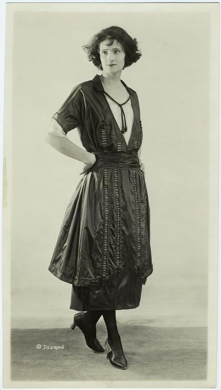 Woman in dark short-sleeved dress with vertical accents, ca. 1921 ...