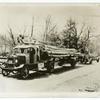 Trucks hauling electric light poles.