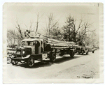 Trucks hauling electric light poles.