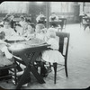 Girls looking up from embroidery at book, Columbus roof
