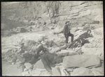 [A Noonday Rest in Marble Canyon, showing well the head of a fall. Snapshot by James Hogue, 1890. From left to right, Travers (standing), Hislop, Kane, Gibson, Ballard, Edwards, Twining (standing), Stanton, McDonald, Brown.]