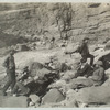 A Noonday Rest in Marble Canyon, showing well the head of a fall. Snapshot by James Hogue, 1890. From left to right, Travers (standing), Hislop, Kane, Gibson, Ballard, Edwards, Twining (standing), Stanton, McDonald, Brown.