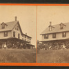 People posed on the porch of a three-store house.