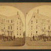 Group portrait of men in front of a three-store house.
