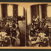 View of women seated at a long table sewing.