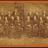 [A group portrait of 9 unidentified men and women pose in front of a painted backdrop.]