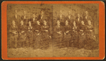 [A group portrait of 9 unidentified men and women pose in front of a painted backdrop.]