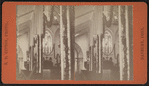 View of a garland-draped church interior with the pastor in the pulpit.