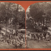 A parade with wagons, men dressed as militia and a band.
