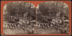 A parade with wagons, men dressed as militia and a band.