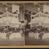 Interior of a large hall showing booths set up for a fair.