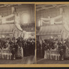 Interior of a large hall showing booths set up for a fair.