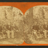 Three gentlemen pose on rustic bench, each holding a walking stick.