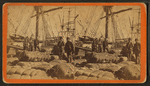 African-American longshore men and bales of cotton on the dock.