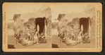 Group of natives eating poi [in front of thatched hut], Hawaiian Islands