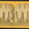 Small group of people sitting in front of a cottage.