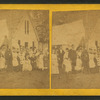 Group portrait of people in front of tent and cottage.