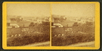 Field scenery in foreground with houses in background.