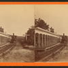 Western Maryland Railraod train standing next to covered platform lined with benches, sign at right reads "Pennsylvania."
