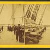 Men on the deck of a ship. Line of shipboard cannons.