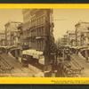 Baltimore street[Street view showing wagons, street car tracks, businesses, signs, awnings].