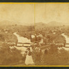 View of a woman looking into the distance with binoculars above Glendale, showing a bridge, a mill, and homes below.