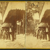 View of a group of men in front of a store, one holding a hose.